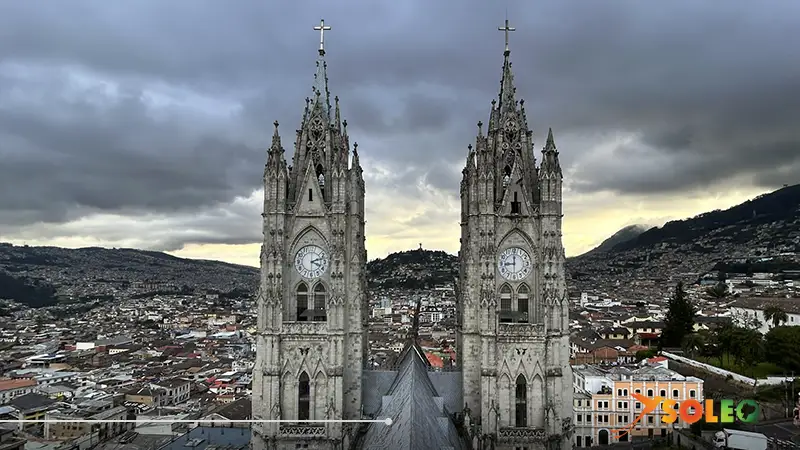 Basílica del Voto Nacional en Quito, con sus torres gemelas neogóticas y vista de la ciudad al atardecer.