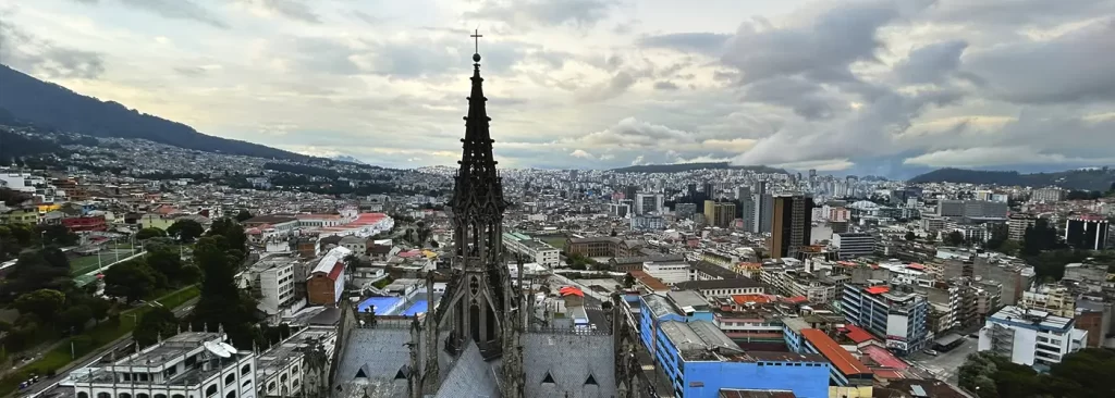 View from the Basilica of the National Vow overlooking northern Quito and modern cityscape under cloudy sky