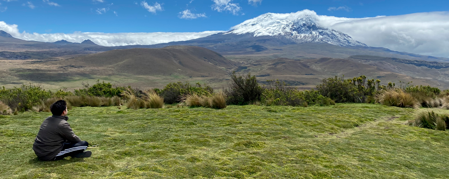 Vista del volcán Antisana en Ecuador con un viajero meditando frente a su cima nevada