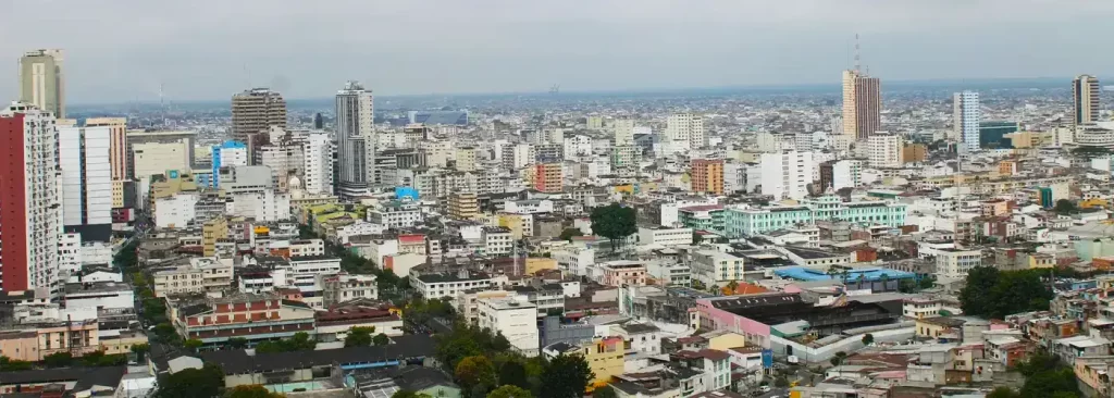 Panoramic view of downtown Guayaquil with modern buildings under a cloudy sky.