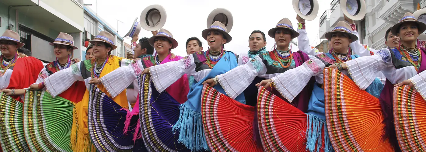 Mama Negra festival dancers wearing vibrant rainbow pleated skirts and traditional Andean costumes during parade in Latacunga Ecuador