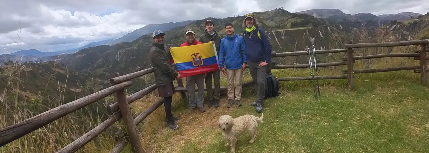 Group of hikers on the Quilotoa Loop trail in Ecuador, approaching the village of Chugchilán with stunning Andean scenery in the background.