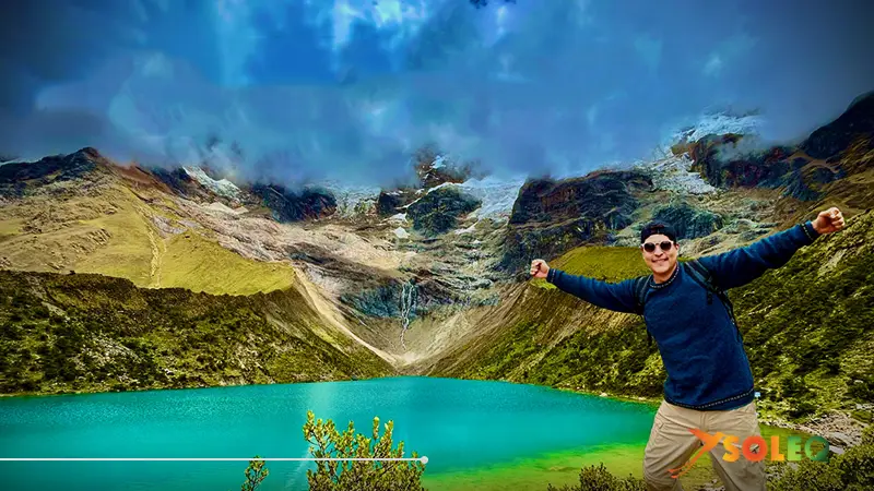 Viajero frente a la laguna turquesa Humantay en Perú, con montañas glaciares al fondo.