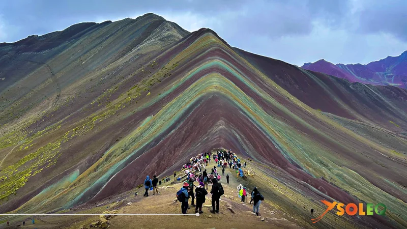 Visitantes en la cresta principal de la Montaña Arcoíris del Perú (Vinicunca): vista de las llamativas capas de colores de la montaña de los siete colores en los Andes peruanos.
