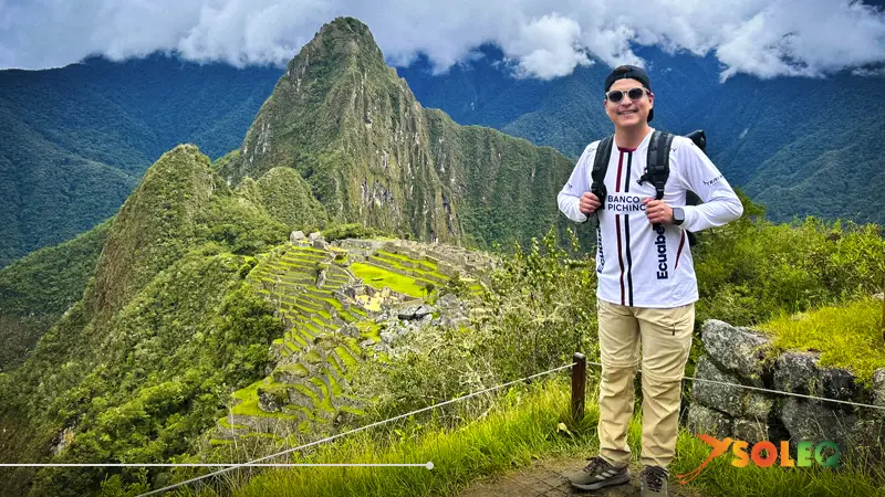 Un mochilero contempla Machu Picchu en Perú con Huayna Picchu al fondo y las verdes terrazas incas.