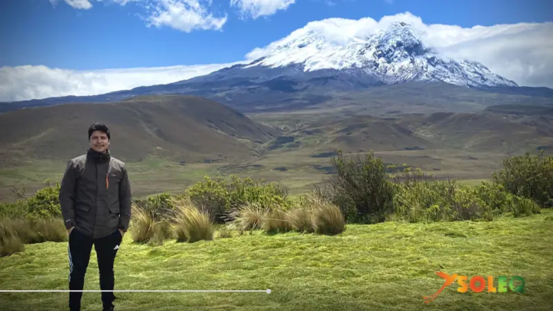 A person in front of the snow-capped Antisana volcano along the Avenue of the Volcanoes in Ecuador